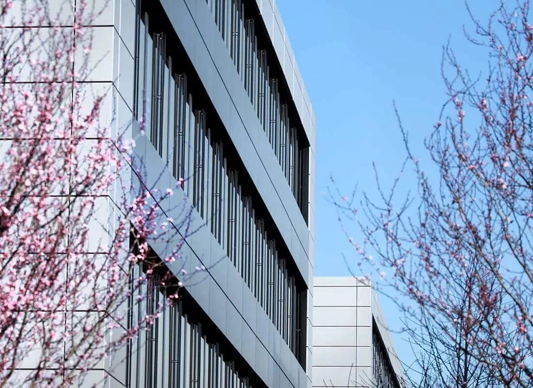 Gebäude mit Glasfassade, davor blühende Bäume